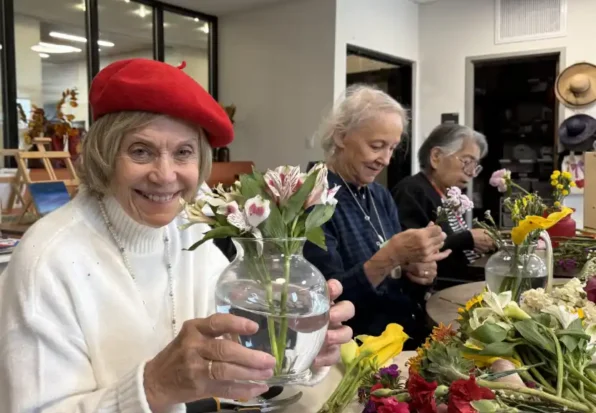 Smiling lady with flowers at Amaran Senior Living {{brizy_dc_image_alt imageSrc=
